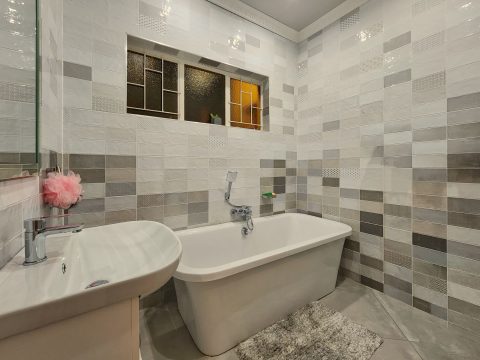 Badezimmer mit Wandfliesen in verschiedenen Formaten und Grautönen